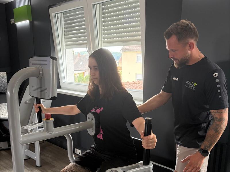 Ein Therapeut betreut eine Patientin an einem EGYM-Kraftgerät